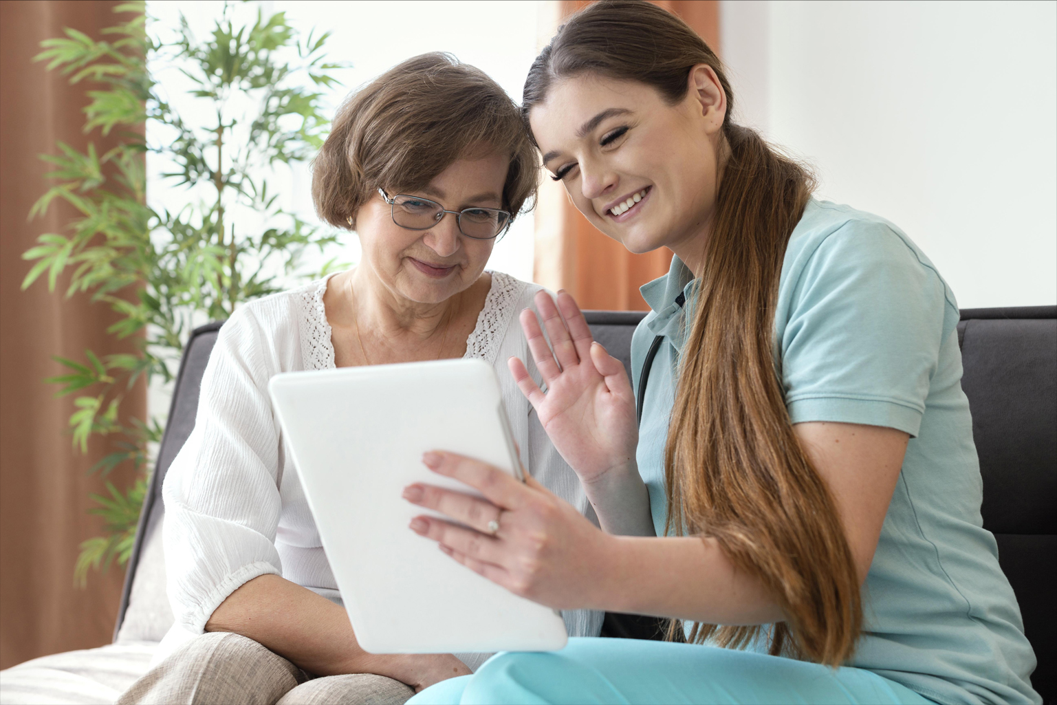 A nurse and a senior lady looking at a tablet.